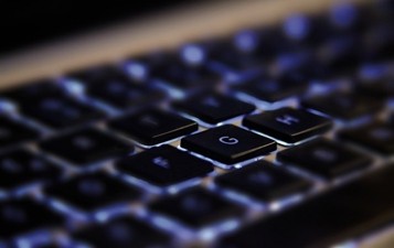 Computer keyboard glowing in a dark room